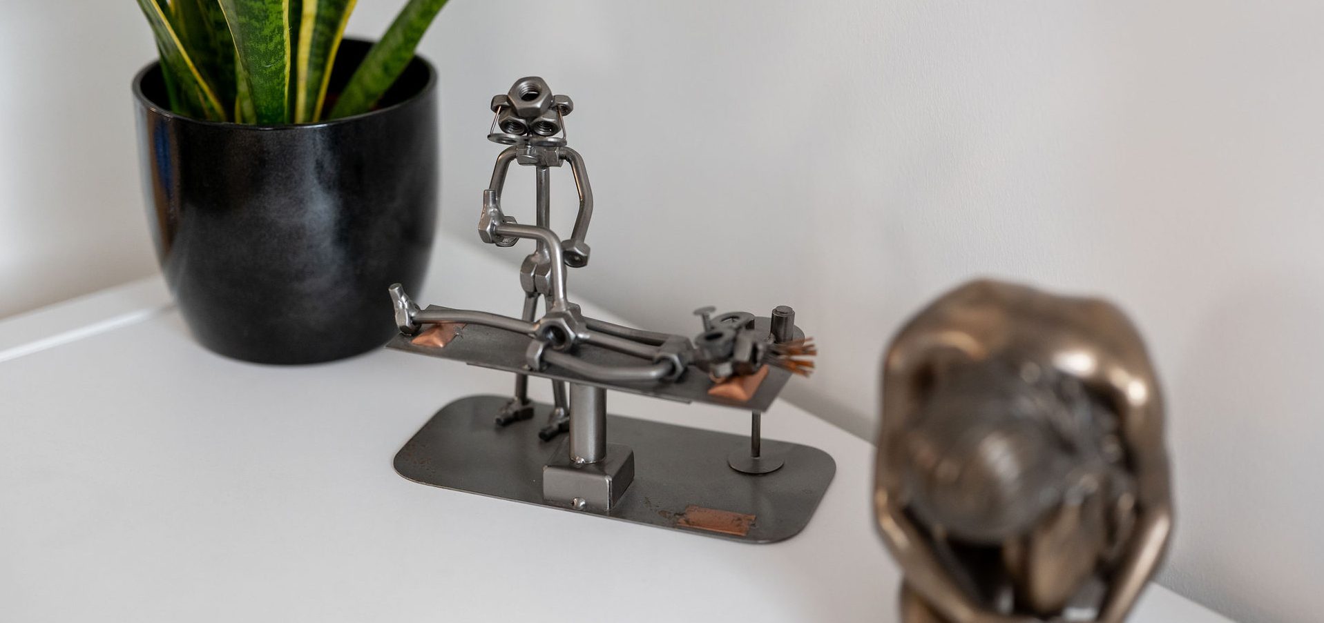 Metal sculpture of a practitioner treating a patient on a treatment couch, displayed at the clinic